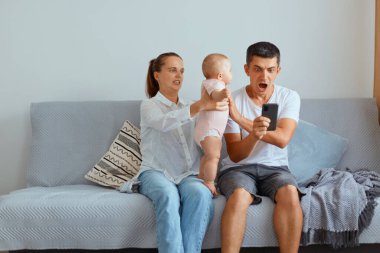 Kapalı alanda, çocukları ışık odasında öksürürken, cep telefonu tutan bir adam, kazanmaktan şok olan, iddiaya giren, hayretle bağıran bir adam, bebeğini babasına veren bir kadın..