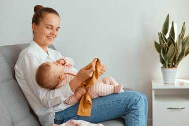 Çekici, genç, yetişkin bir annenin küçük kızıyla koltukta oturup mutluluğunu ifade ettiği, mutlu bir şekilde gülümsediği, annelik ve çocukluk..