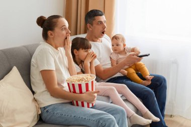 Kanepede oturup patlamış mısırla korku filmi izleyen, birlikte televizyon seyrederken şok olmuş duygularını ifade eden, boş zamanlarını birlikte geçiren şaşırmış aile portresi..