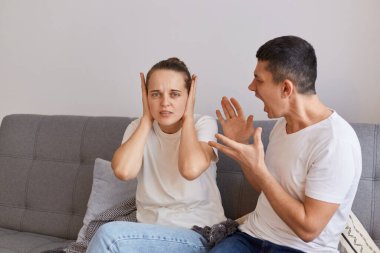 Kapalı alanda genç bir çiftin çatışması, kızgın öfkeli bir adamın kanepeye oturup kollarını kaldırarak karısına bağırması, kavga etmesi, ilişki sorunları....