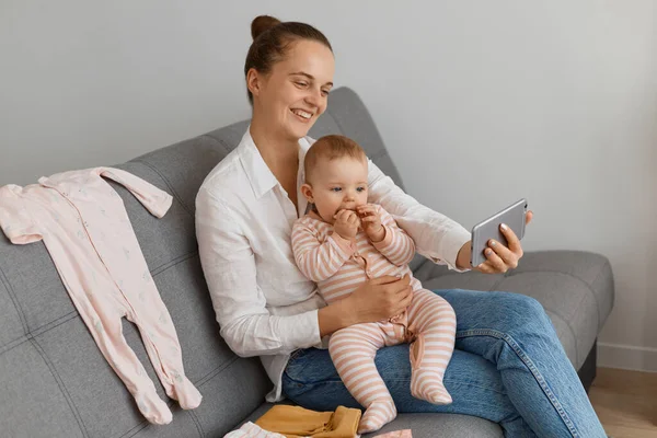 Satisfied Woman Wearing White Shirt Jeans Sitting Sofa Her Baby — Stock Photo, Image