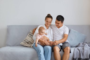 Evde mutlu bir anne, evde kızıyla oturan bir baba, kanepede birlikte vakit geçiren, sevgisini, kibarlığını ve mutluluğunu ifade eden, tatlı çocuklu bir aile..