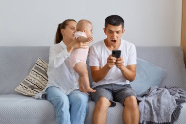Elinde bebekle kocasının dikkatini çekmeye çalışan kadının portresi, akıllı telefonda video oyunu oynayan adamın heyecanlı ve şok olmuş olması, umutsuzluktan çığlık atması..