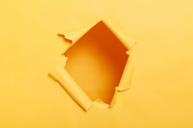Big paper hole in center of yellow background, blank space to insert your advertising content promotion or text information, torn ripped wall.