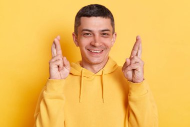 Sıradan bir kapüşonlu giyen pozitif bir adam sarı arka planda yalnız poz veriyor şans dilemek için şans diliyor, şans diliyor, başarı diliyor, hoş bir şeyler diliyor..