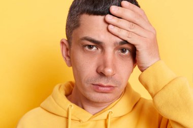 Sarı arka planda yalnız poz veren umutsuz bir kapüşonlu adam, kötü anılar için kendini suçlayıp duruyor, affedilemez hatalar, üzüntü ve utanç duygularını ifade ediyor..