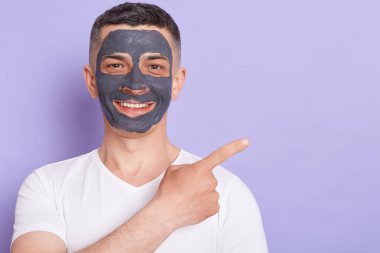 Beyaz tişörtlü, yüzünde kozmetik maske olan, yaşlanmayı önleyici işlemler yapan, reklam veya tanıtım metinleri için karınca fotokopi alanını gösteren kapalı bir fotoğraf..