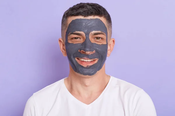 Indoor Shot Van Vrolijke Glimlachende Man Met Kleimasker Zijn Gezicht — Stockfoto