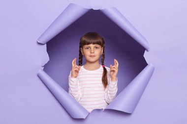 İç mekânda örgü örgülü sevimli küçük bir kızın mor arka planda buluşunu çekerken, umut dolu görünüyor..