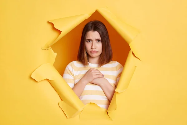 Портрет Грустной Расстроенной Женщины Полосатой Рубашке Позирующей Желтой Бумажной Дыре — стоковое фото