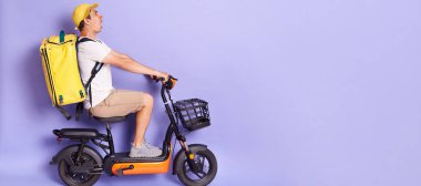 Yandan bakıldığında, termo sırt çantalı kurye portresi giyen, elektrikli scooterla yiyecek getiren, korkmuş bir ifadeyle ileriye bakan, kazayı önleyen, mor arka planda izole edilmiş bir kurye.