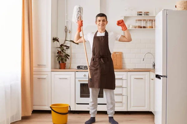 Portret Przystojnego Mężczyzny Brązowym Fartuchu Pomarańczowych Rękawiczkach Kończący Sprzątanie Domu — Zdjęcie stockowe