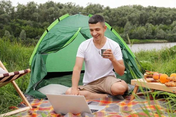 Horizontal Shot Delighted Caucasian Guy Freelancer Sitting River His Tent — Φωτογραφία Αρχείου