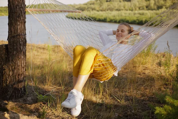 Horizontal Shot Caucasian Happy Delighted Woman Sitting Hammock Water Posing — Zdjęcie stockowe