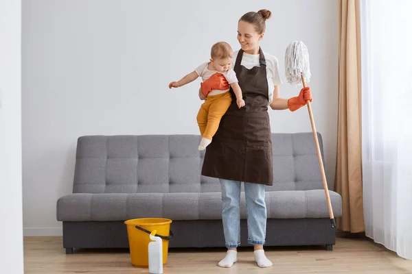 Portrait Smiling Positive Woman Wearing Brown Apron Mop Little Toddler — Stock Fotó