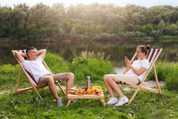 Outdoor Shot Young Couple Sitting Deck Chair Talking River Relaxed — Photo