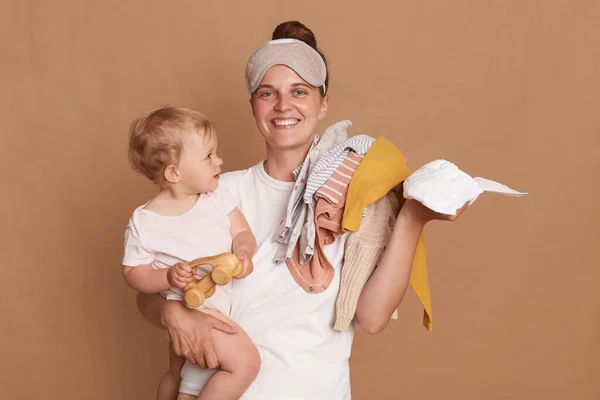 Sonriente Joven Madre Con Peinado Moño Sosteniendo Hija Pequeña Ropa —  Fotos de Stock