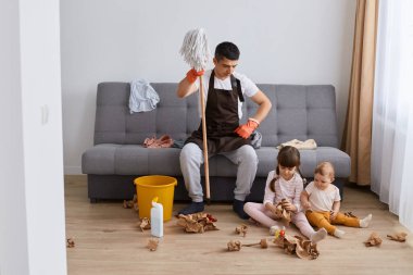 Kahverengi önlük giymiş esmer bir adamın evini temizlerken, ev işlerini yaparken, el paspası tutarken, çocuklarının yanında poz verirken çekilmiş..