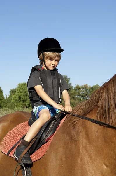 Giovane ragazzo cavalcare un cavallo — Foto Stock