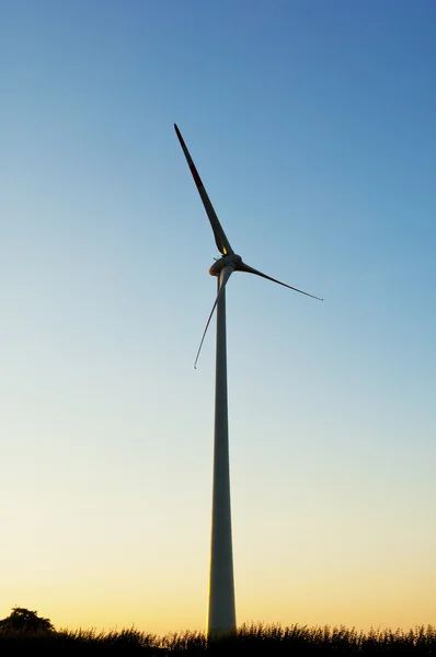 Silueta de un aerogenerador eléctrico sobre fondo del atardecer — Foto de Stock