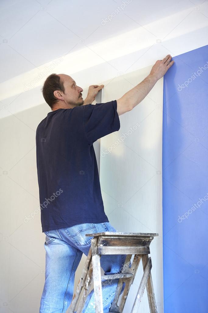 man putting up wallpaper