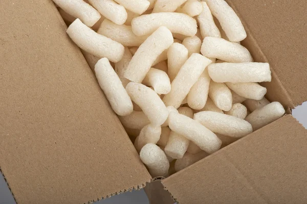 Caixa de papelão com amendoim de isopor de embalagem amarelo, isolado em — Fotografia de Stock