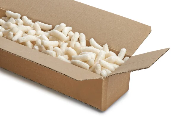 Una scatola di cartone con imballaggio giallo in polistirolo arachidi, isolato — Foto Stock
