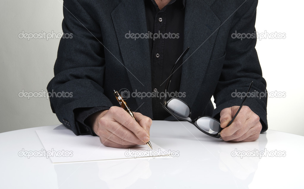 Close up of the hands of a businessman in a suit signing or writ