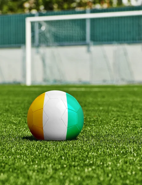 Balón de fútbol con bandera de Costa de Marfil en el césped en el estadio —  Fotos de Stock