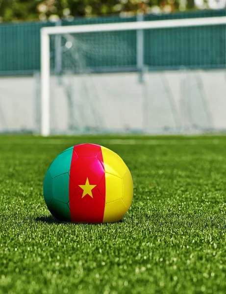 Bola de futebol com bandeira dos Camarões na grama no estádio — Fotografia de Stock
