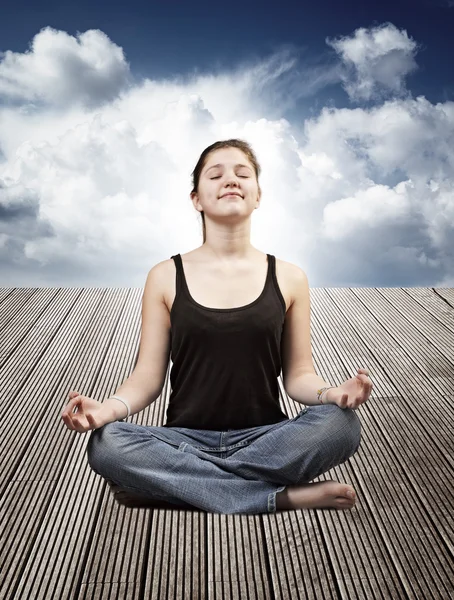 Portrait of a beautiful young woman sitting in yoga pose on a wo — Stock Photo, Image