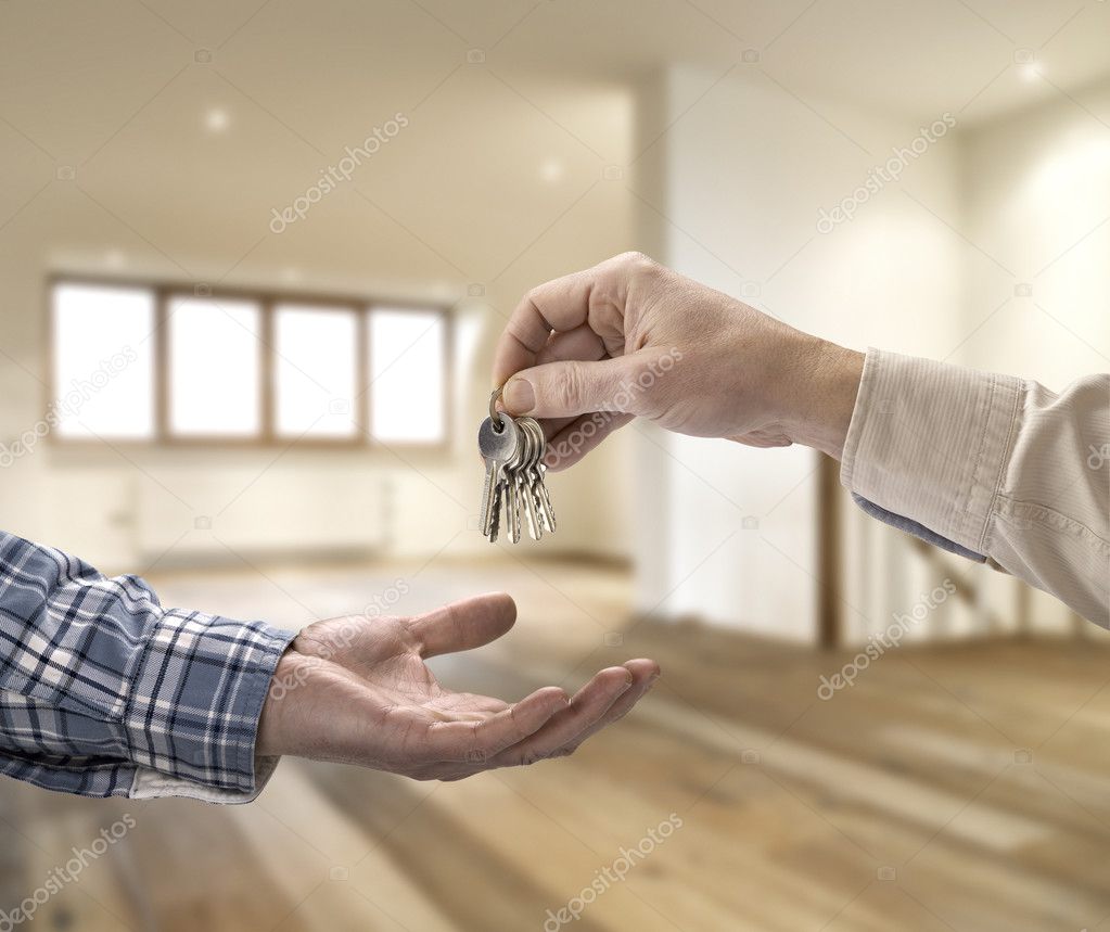 Realtor giving house key to buyer in empty room