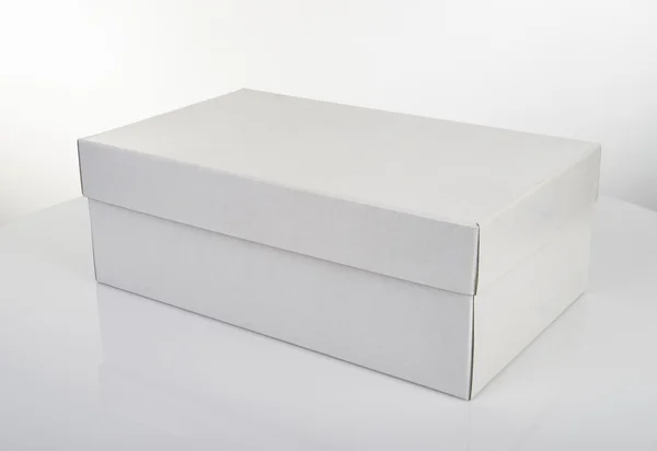 Caja de zapatos blanca aislada en mesa blanca — Foto de Stock