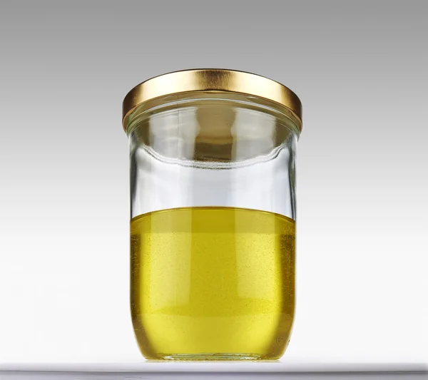 Olive oil into closed glass jar — Stock Photo, Image