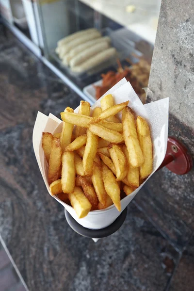Potatoes fries in a little white paper bag hanging at the wall f — Stock Photo, Image