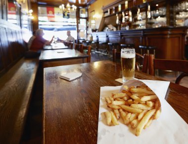 ahşap tahta üzerinde bir küçük beyaz kağıt torba patates kızartması