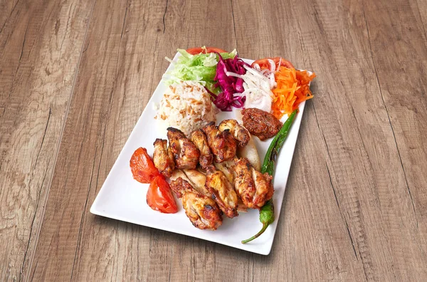 White plate with Chicken drumsticks  and vegetables on wooden table