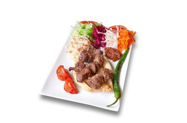 Kuzu kebabı ve sebzeli beyaz tabak.