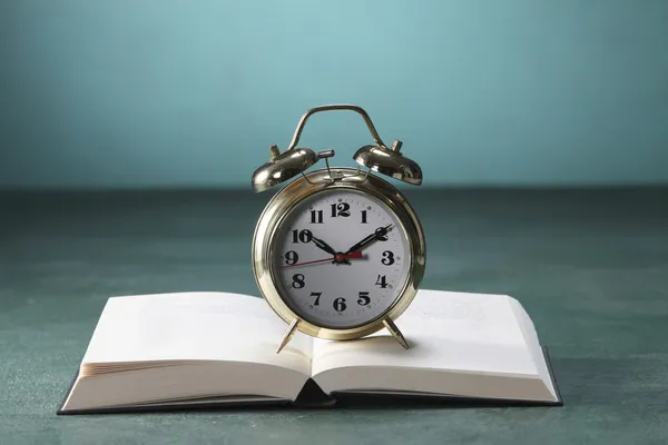 Alarm clock on open book — Stock Photo, Image