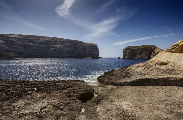 Azure pencere rock Malta Adası, gozo, dweira lagoon, bir yelkenli tekne ve kayalık sahil yakınındaki — Stok fotoğraf