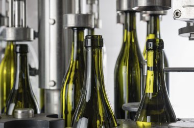 İtalya, Sicilya, şarap şişeleri ile şarap şarap fabrikasında bir sanayi makinesi tarafından doldurulur.