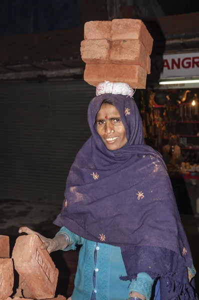 Indisk kvinna som bär tegel på hennes huvud — Stockfoto