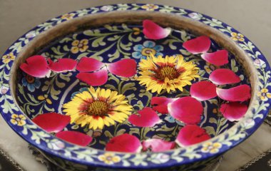 su dolu bir kabın içinde gül yaprakları