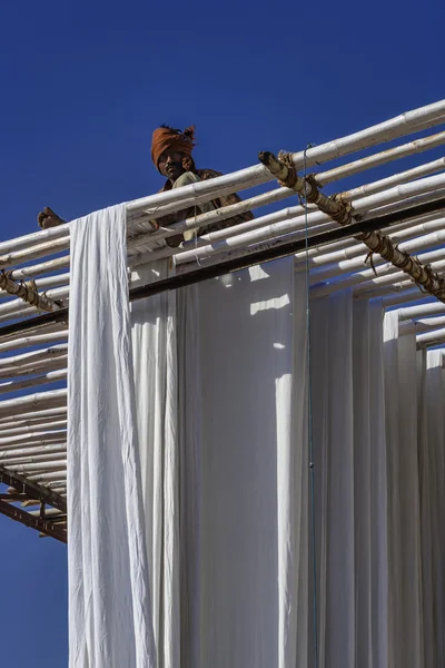 Homem indiano pendurado roupas de algodão para secar sob o sol — Fotografia de Stock