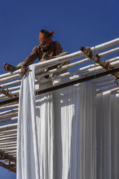 Homem indiano pendurado roupas de algodão para secar sob o sol — Fotografia de Stock