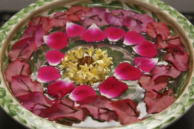 su dolu bir kabın içinde gül yaprakları