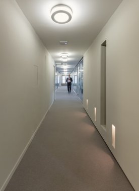 bir ofis koridorunda yürürken iş adamı