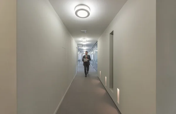 Homem de negócios caminhando em um corredor de escritório — Fotografia de Stock