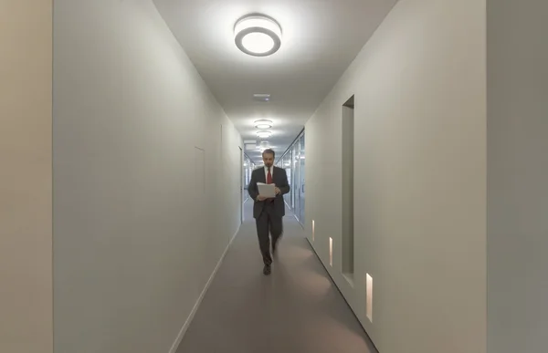 Business man walking in an office corridor — Stock Photo, Image