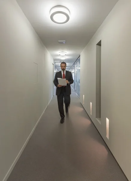 Business man walking in an office corridor — Stock Photo, Image